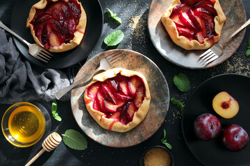 Tasty cake with plums on dark background. Top view with copy space. Healthy food.