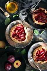 Tasty cake with plums on dark background. Top view with copy space. Healthy food.