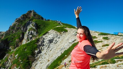 外国人女性が山頂で手を伸ばしている写真