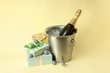 New Year composition with champagne and gifts on light yellow background