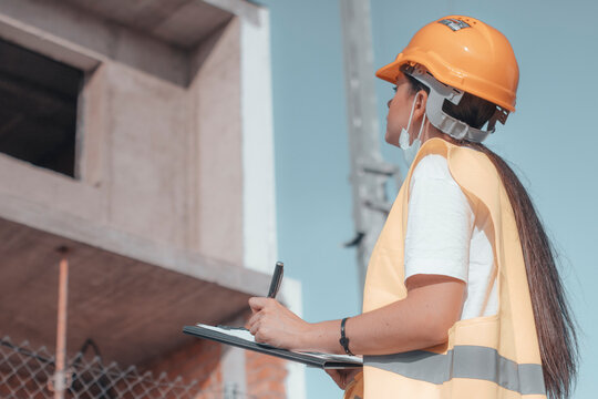 Arquitecta de obra estudiando el perimetro del edificio para su construcci&oacute;n junto con otros empleados de obra asegurados con sus cascos de protecci&oacute;n mientras se planifica la maquetaci&oacute;n