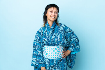 Young woman wearing kimono over isolated blue background laughing