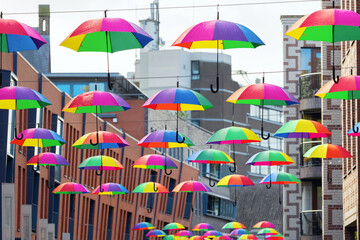 Fototapeta na wymiar city street with rainbow colored umbrellas at a line in Nijmegen, Netherlands