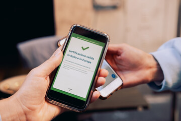 Checking vaccination certificate or negative test for covid-2019 Green Pass at the entrance to a restaurant in Italy.