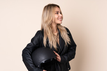 Russian girl with a motorcycle helmet isolated on beige background happy and smiling