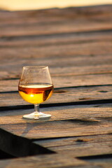 a glass of wine on a wooden pier at sunset