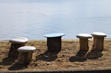 Mushroom-shaped seats made from wood logs along the shore of Lake Trasimeno (Umbria, Italy, Europe) - 464255626