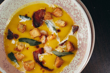 Tasty pumpkin cream soup with prawns and croutons.
