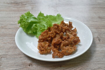 deep fried crispy salty chicken meat and skin on plate eat couple fresh lettuce vegetable salad