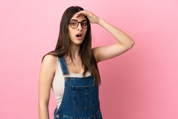 Young caucasian woman isolated on pink background doing surprise gesture while looking to the side