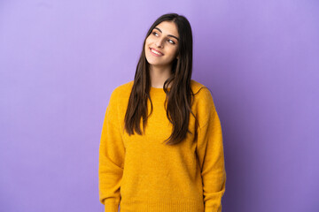 Fototapeta premium Young caucasian woman isolated on purple background thinking an idea while looking up