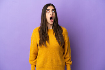 Young caucasian woman isolated on purple background looking up and with surprised expression