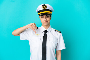 Airplane pilot caucasian woman isolated on blue background showing thumb down with negative expression
