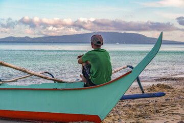 Traditional village fishermen waiting for the tide to change and watching the Taal volcano cloud...