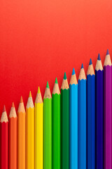 Colour pencils arranged diagonally on a red vertical paper background.