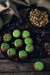 pistachio macarons on wooden background with raspberries