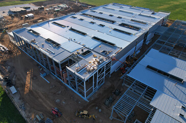 Warehouse Construction from metal structure. Industrial building on light gauge steel framing. Frame of modern hangar or factory. Construction site with steel structure warehouse. Top view on a roof.