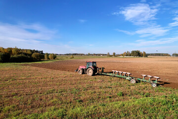 Obraz premium Tractor with Plough on Plowed. Ploughing and Soil Tillage. Agricultural Tractor on Cultivation Field for Sowing Seeds. Tractor During Field Cultivating. Planting and Seeding Equipment.