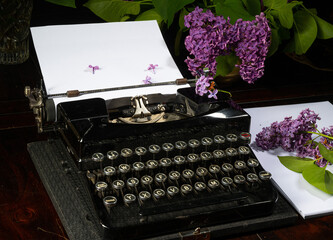 old typewriter, sheet of paper and lilac
