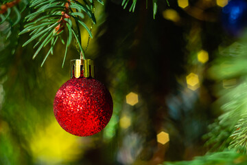 Christmas tree with bright beautiful red ball close up on a blurry shiny background. Christmas and New Year concept.