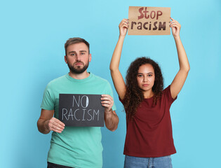 Young man and African American woman holding signs on turquoise background. Racism concept