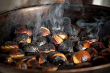Close up view of chestnuts roasting in a pan with smoke