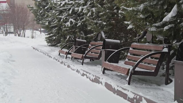 Benches in the square during the snow-fall. Winter in Siberian city.