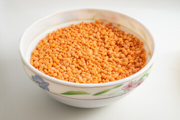 White Bowl filled with raw red  lentil on white background