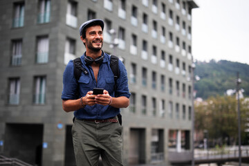 Young stylish man using the phone outdoors. Fashion happy businessman outdoors