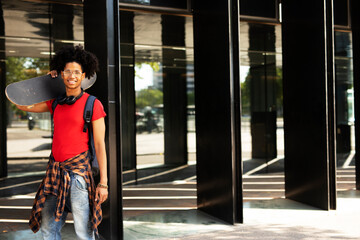 Obraz premium Portrait of happy african-american man with skateboard. Young fashion man with skateboard outdoors.