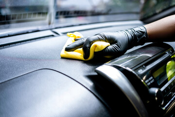 Cropped image of mature male worker cleaning car dashboard