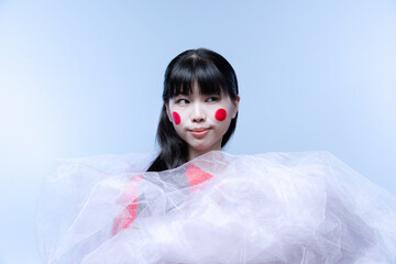 Close-up portrait of young amazing Japanese girl with bright stage make-up isolated on white studio background.