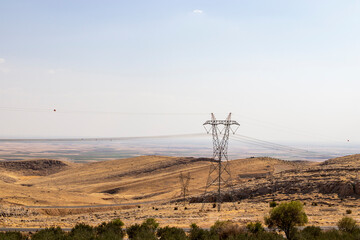 Fototapeta na wymiar High voltage line, transmission wires and power poles in steppe vegetation.