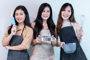 Three Asian female friends Having fun together, helping each other make homemade cakes is an activity to build good relationships with each other. 
