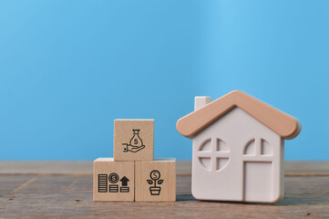 Toy house and wooden blocks with property investing symbols