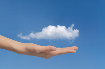 Woman's hand holds cloud in the palm of her hand, close-up on blue sky. Concept of data exchange and communication