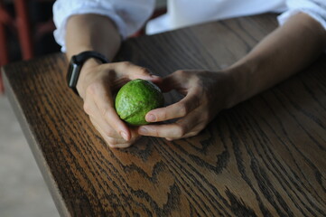 hands holding ripe green lime