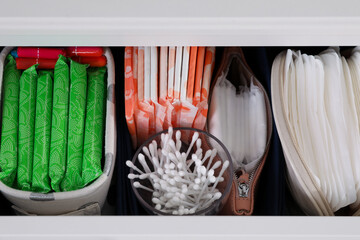 Open cabinet drawer with menstrual pads, tampons and cotton buds, above view