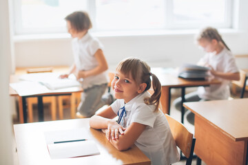 Serious pensive cute girl child at a school desk, learning concept, private small school, extracurricular activities