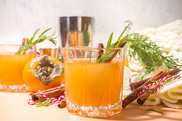 Autumn alcohol drinks. Spicy boozy gin persimmon cocktail with rosemary and cinnamon