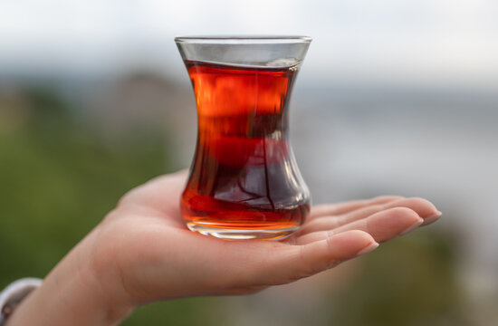 Tea cup armudas on woman hand, traditional Turkish tea against background of the Istanbul, Sile cityscape. Special glasses of Armuda