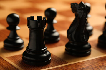 Wooden chessboard with game pieces, closeup view