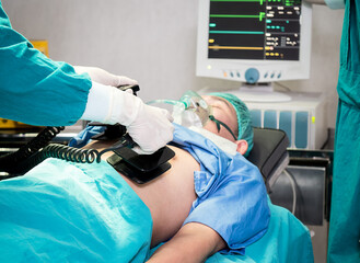 Doctors give resuscitation to a male patient in the operation room, rescue safe life patients with automated external defibrillator emergency moment concept