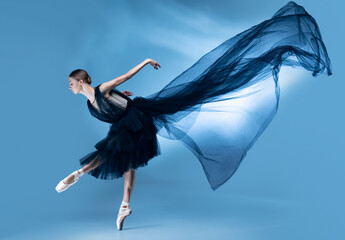 Young and graceful ballet dancer in black stage outfit, dress isolated on white blue studio...