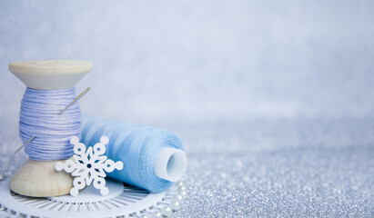 thread and needle on a silver background. Sewing accessories. Winter-themed sewing