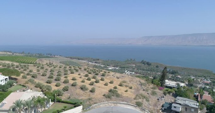 Aerial shot at sunset above Golan Heights and Tiberias with Galilee sea or Kinneret at Jordan valley in North of Israel. Drone above open fields with orange green landscapes and mountains with clear