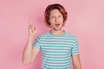 Photo of creative genius man raise finger up empty space have idea wear casual blue striped t-shirt on pink background