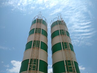 Cement silo, green and white painted tower against the blue sky