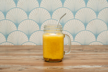 Delicious passion fruit smoothie in glass with metal straw on wooden table