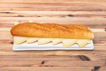 Baguette bread sandwich with chopped Manchego cheese on white plate